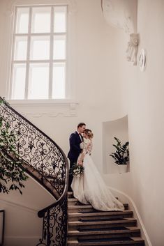 a bride and groom are standing on the stairs at their wedding reception in an elegant building