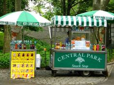 a green and white food cart sitting in the middle of a park