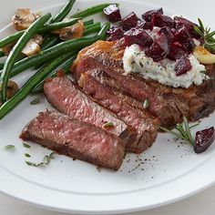 steak, green beans and mashed potatoes on a white plate with cranberry sauce