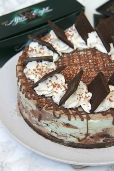 a cake with chocolate and cream toppings on a white plate next to some books