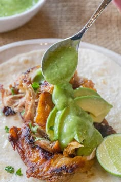 a close up of a taco with guacamole and sauce on it