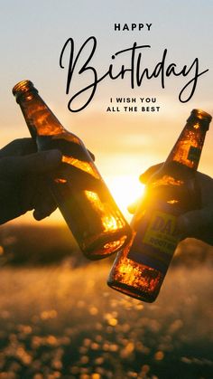 someone holding two beer bottles in their hands with the sun setting behind them and text happy birthday i wish you all the best