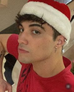 a young man wearing a santa hat looking at the camera