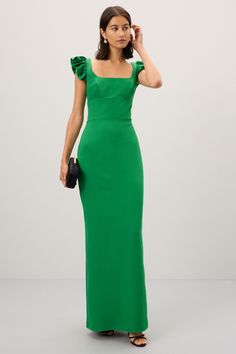 a woman in a green dress posing for the camera with her hand on her head