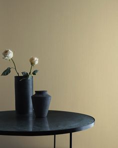 two black vases with white flowers on a table