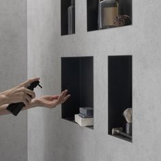 a person holding a spray bottle in their hand near some shelves with bottles on them