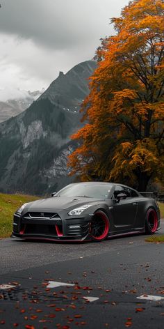 a black sports car parked on the side of a road in front of a mountain