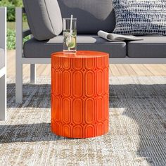 an orange stool sitting on top of a wooden floor next to a couch and table