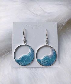 a pair of earrings with blue waves on them