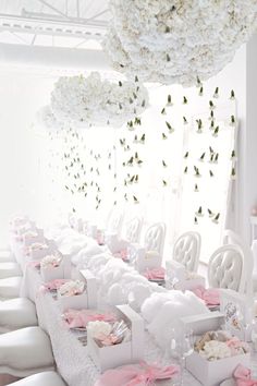 a long table with white chairs and pink napkins on it is decorated with flowers