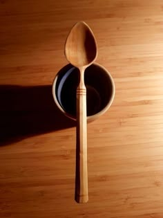 a wooden spoon sitting in a bowl on top of a wooden table next to a black plate