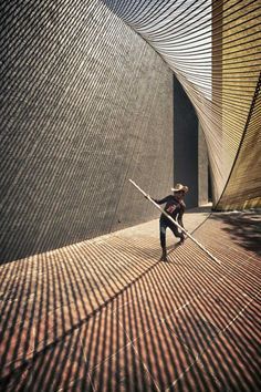 a person with a hat and cane standing in front of a wall that has lines on it