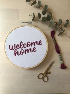 a cross - stitch pattern with the words welcome home and a pair of scissors next to it