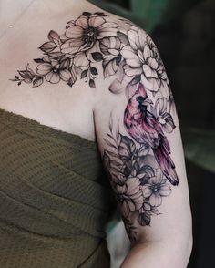 a woman's arm with flowers and a bird tattoo on her left shoulder,