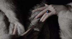 a woman's hand with a ring on top of her finger and fur coat