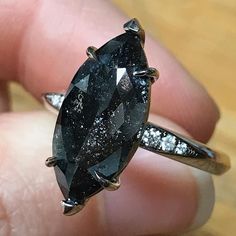 a close up of a person's hand holding a ring with a black diamond