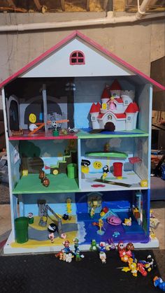 a doll house with lots of toys on top of the shelves in front of it