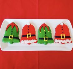 three decorated cookies on a white plate with red and green decorations, including santa's hats