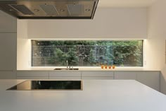 a modern kitchen with white counter tops and stainless steel appliances in front of a large window