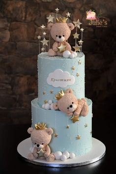 a three tiered blue cake with teddy bears on top and stars around the edges