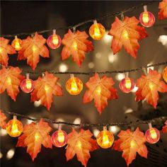 the lights are decorated with autumn leaves on strings and strung by twine stringing