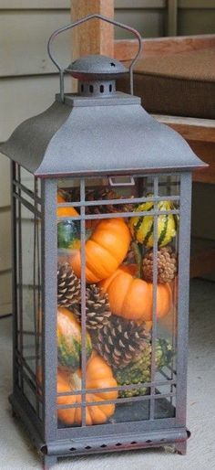 a lantern filled with pumpkins and pine cones