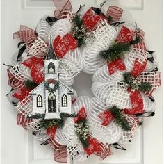 a christmas wreath with a church on it and red ribbon around the front entrance door