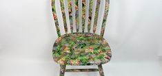 a wooden chair with floral fabric on it's back and seat, against a white background