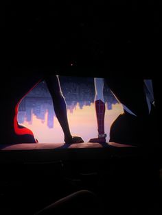 two people standing in the dark with their feet up and legs down, facing each other