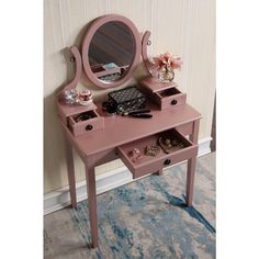 a pink vanity with drawers and a mirror