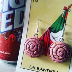 a pair of pink earrings sitting next to a can of soda