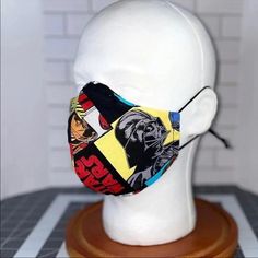 a white mannequin head wearing a face mask with comic covers on it