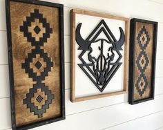 three wooden wall hangings on the side of a white building with black and brown designs