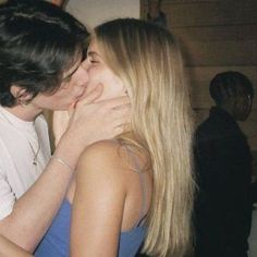 two people are kissing each other in front of a crowd at a party or social gathering