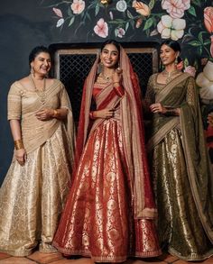 three women standing next to each other wearing different colored dresses and sari's