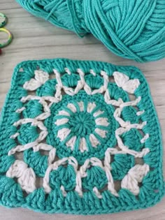 a crocheted square is sitting on the table next to yarn