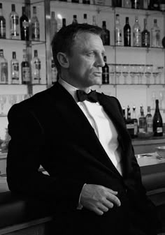 a man in a tuxedo sitting at a bar