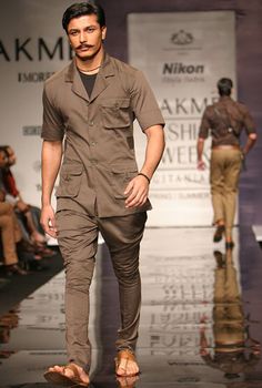 a man is walking down the runway at a fashion show