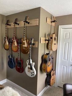 several guitars are hanging on the wall in a room with carpeted floor and door