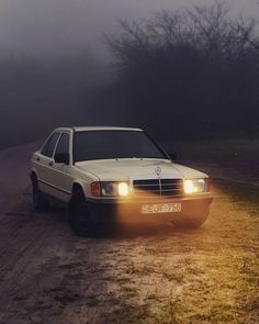 a white car parked on the side of a dirt road