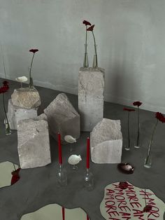 several vases with flowers in them sitting on the floor next to mirrors and candles