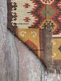 an old rug is laying on top of a stone wall and has fringed edges