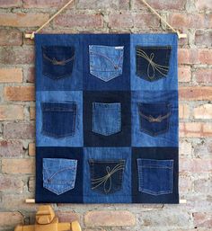 a blue patchwork wall hanging on a brick wall with scissors in the back pocket