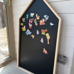 a black board with stickers on it in front of a window next to a door