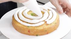 a person is decorating a cake with icing on the top and around it