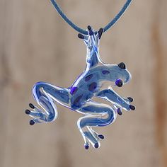 A spry blue glass frog with black accents handblown with a pipette and with torch worked details hangs from a blue waxed cotton cord in this pendant necklace. Handcrafted by Costa Rican artisan Guisselle Mora the frog has tiny air bubbles captured in the glass characteristic of handblown glass. A sliding knot in the cord allows the necklace length to easily be adjusted. Glass Jewelry Pendant, Whimsical Glass Necklace For Gifts, Fused Glass Keychains Animal, Unique Green Glass Necklace, Blown Glass Pendant Necklace, Unique Glass Necklace Pendant Folksy, Handblown Glass Pendant, Frog Pendant Necklaces, Glass Frog