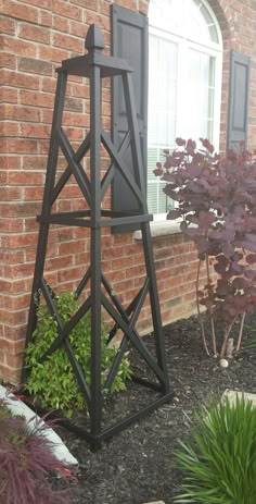 a tall metal tower sitting in front of a brick building next to a planter