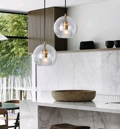 a kitchen with marble counter tops and hanging lights