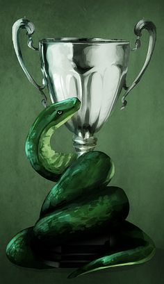 a silver trophy sitting on top of a cucumber next to a green snake