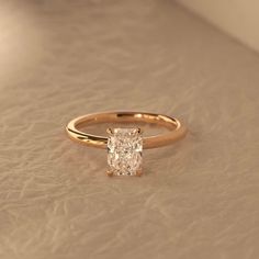 a close up of a ring with a diamond in the center on a beige surface